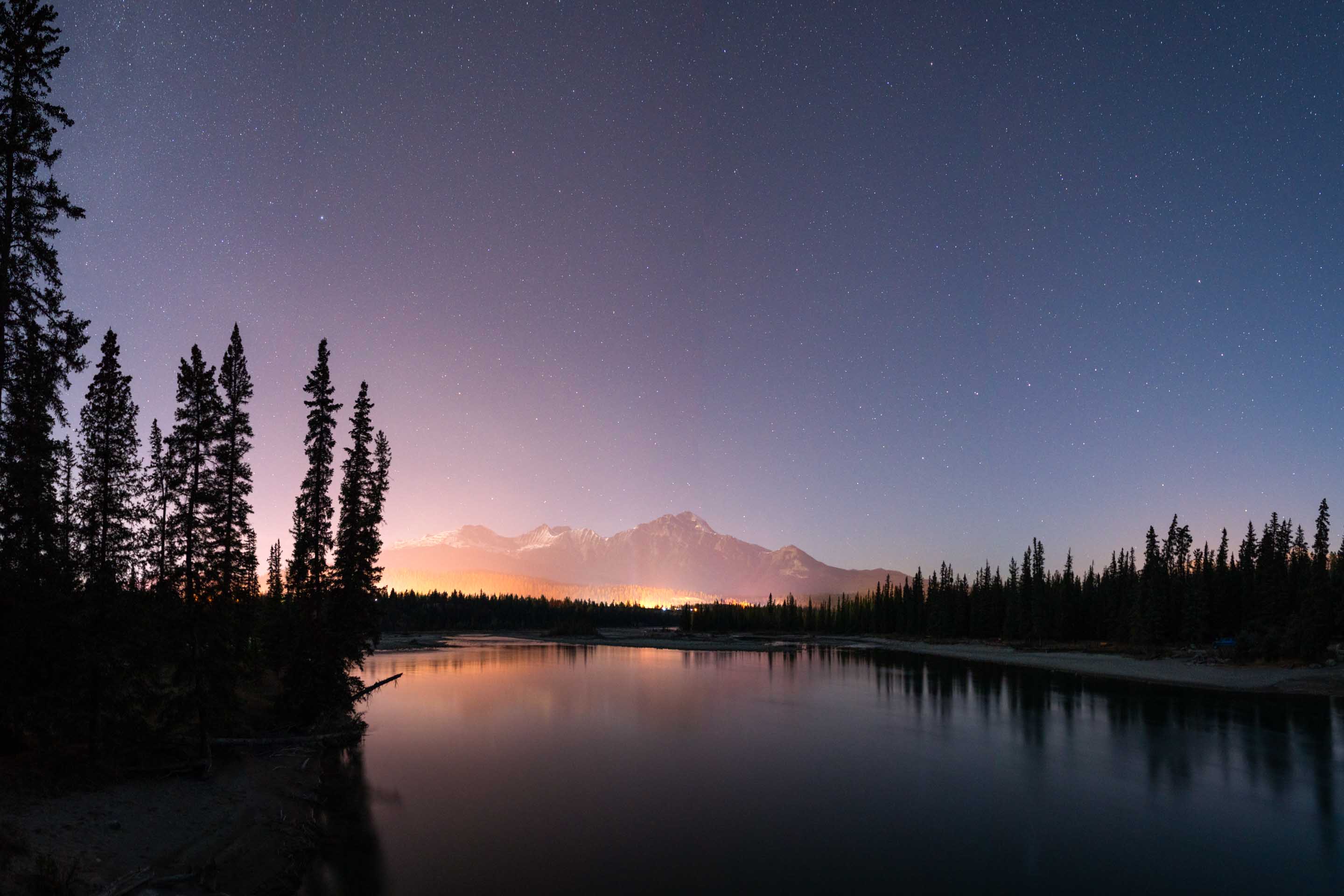 From Old Fort Point, this image shows the small amount of light pollution in Jasper National Park. Between this viewpoint and the distant Pyramid Mountain, the town of Jasper barely affects the view of the night sky.