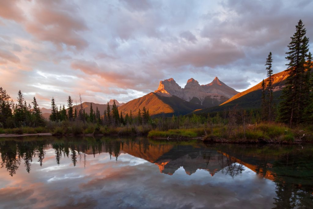 Sunrise hits the Three Sisters mountain range in Canmore, Alberta, foreshadowing a beautiful day in the Canadian Rockies.